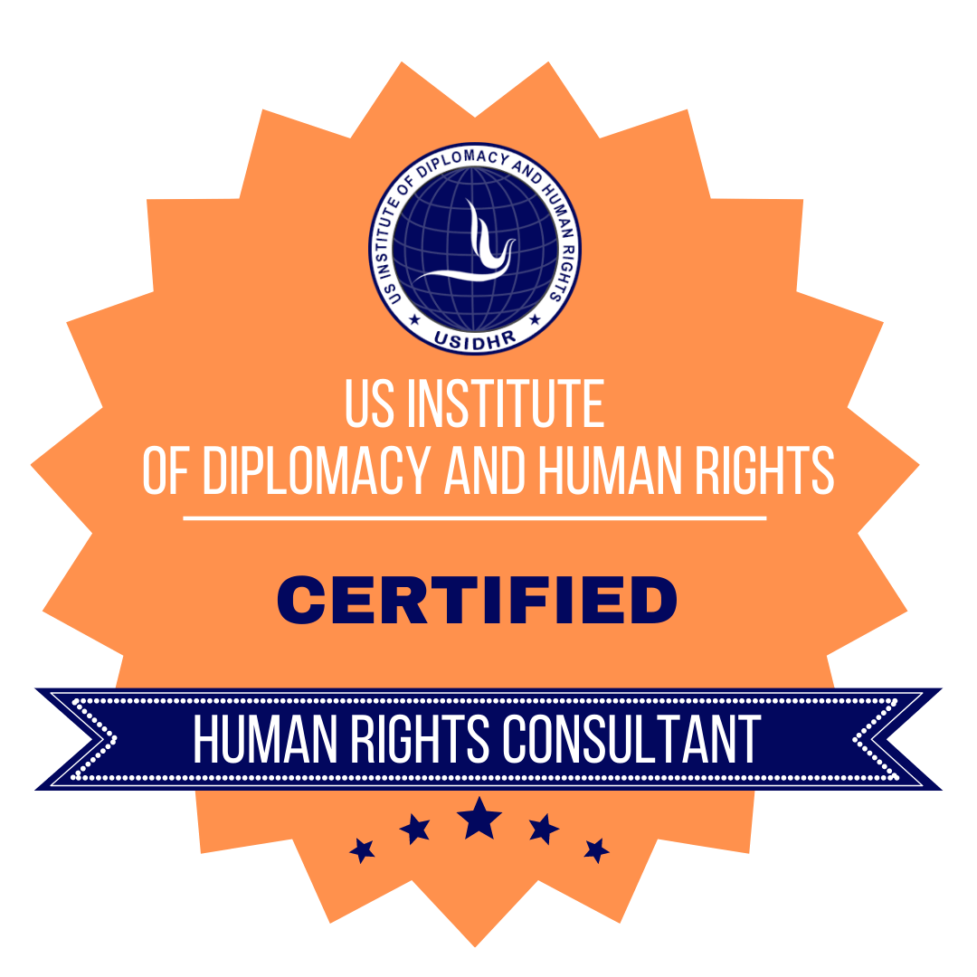 A certification badge for a ‘Human Rights Consultant’ from the US Institute of Diplomacy and Human Rights (USIDHR). The badge features an orange sunburst shape with the USIDHR logo at the top, which includes an abstract white dove on a blue globe background surrounded by stars and the title of the institute. Below the logo, the text reads, ‘US Institute of Diplomacy and Human Rights’ in white, followed by ‘Certified’ in bold blue text. At the bottom, a blue ribbon banner contains the text ‘Human Rights Consultant’ in white text, flanked by stars.