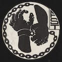 Logo graphic for the Free Southern Theatre. This image depicts a circular design with a black and white motif. Inside the circle, there is a broken chain surrounding an illustration of two hands, one hand shackled and the other breaking free. To the right of the hands, there are hand-drawn letters ‘FST.’ The design is simple yet powerful, conveying a message of liberation and breaking away from oppression.