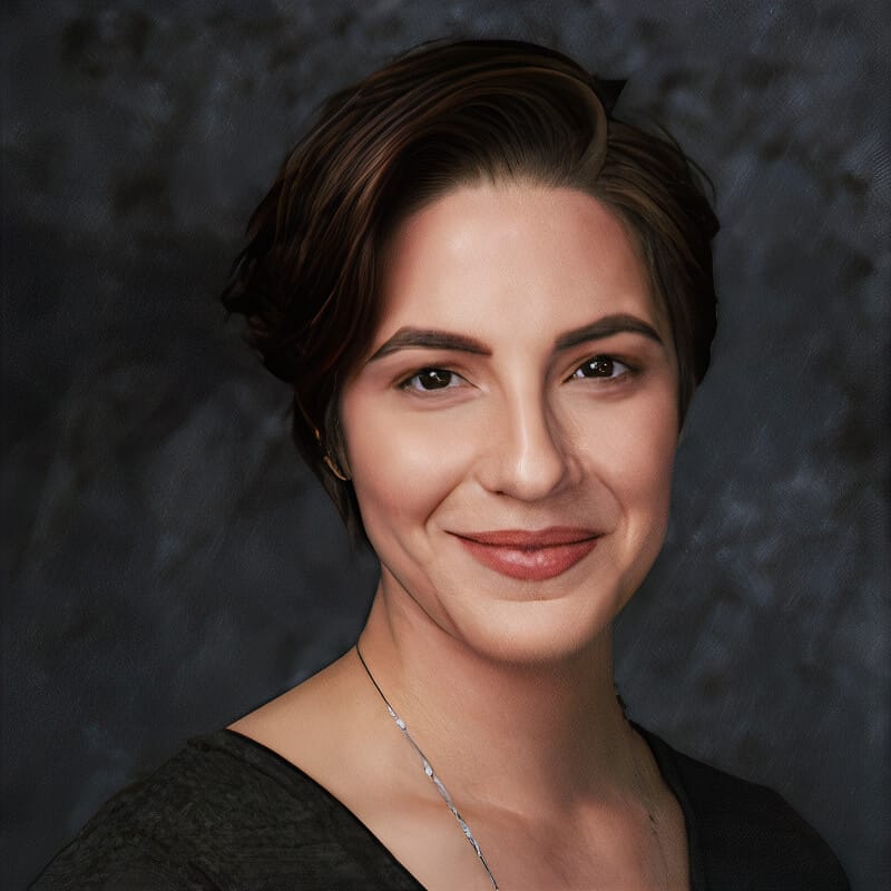 Headshot of Heather La Kor, a woman with short, dark brown hair styled neatly, wearing a subtle smile. The individual has light skin, well-defined eyebrows, and a natural makeup look, with soft lipstick and minimal accessories, aside from a delicate necklace. The background is a dark, textured gradient, providing contrast and making the subject stand out. The expression is calm and friendly.